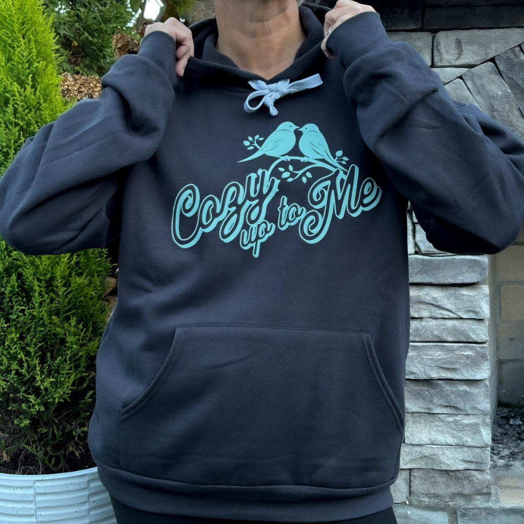 person wearing charcoal gray sweatshirt with mint green text saying 'cozy up to me' & lovebird graphic.
