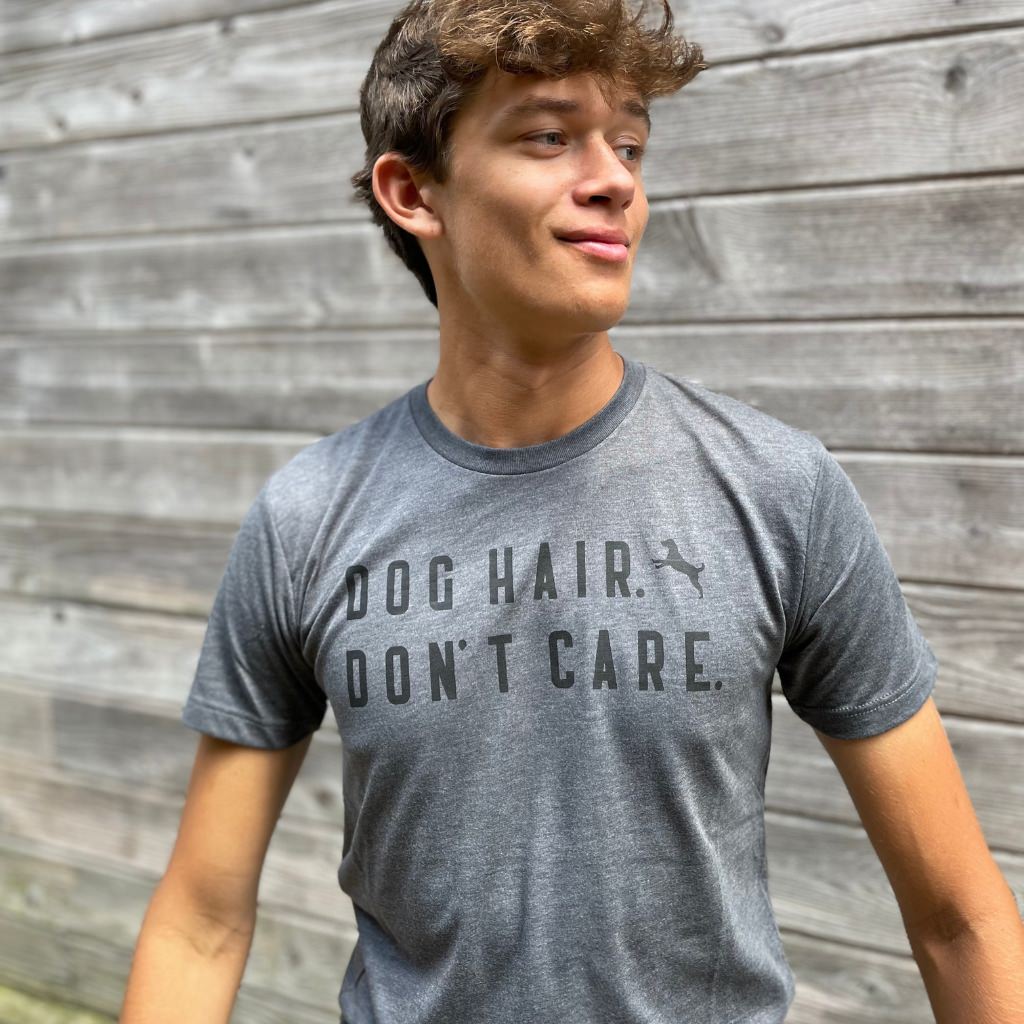 dog hair don't care black text saying on gray unisex tshirt.  dog tshirt.  dog apparel for humans.  young man wearing dog tshirt.