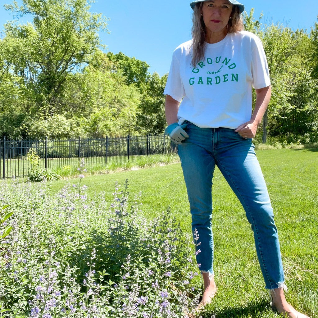 organic cotton apparel.  organic cotton tshirt for women.  organic tshirts women.  organic tees for women.  organic cotton tshirts. 
 white organic cotton tshirt with green text saying ground and garden.  wellness apparel.  garden lover.  grounding tshirt.  gardening tshirt.
woman wearing organic cotton printed tshirt in the garden.