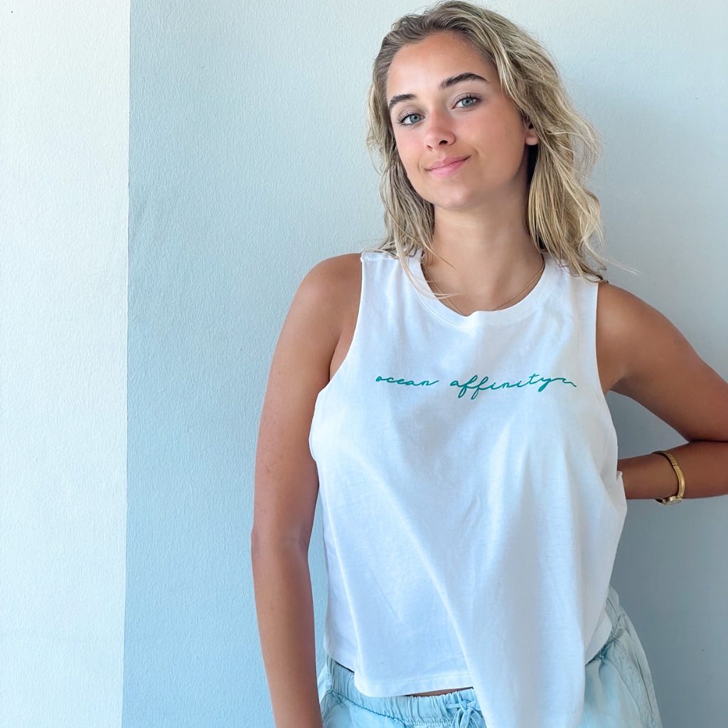 ocean affinity turquoise green script text on bright white racer back crop tank.  beach apparel.  ocean lover tank top.  woman wearing airy white beach tank.