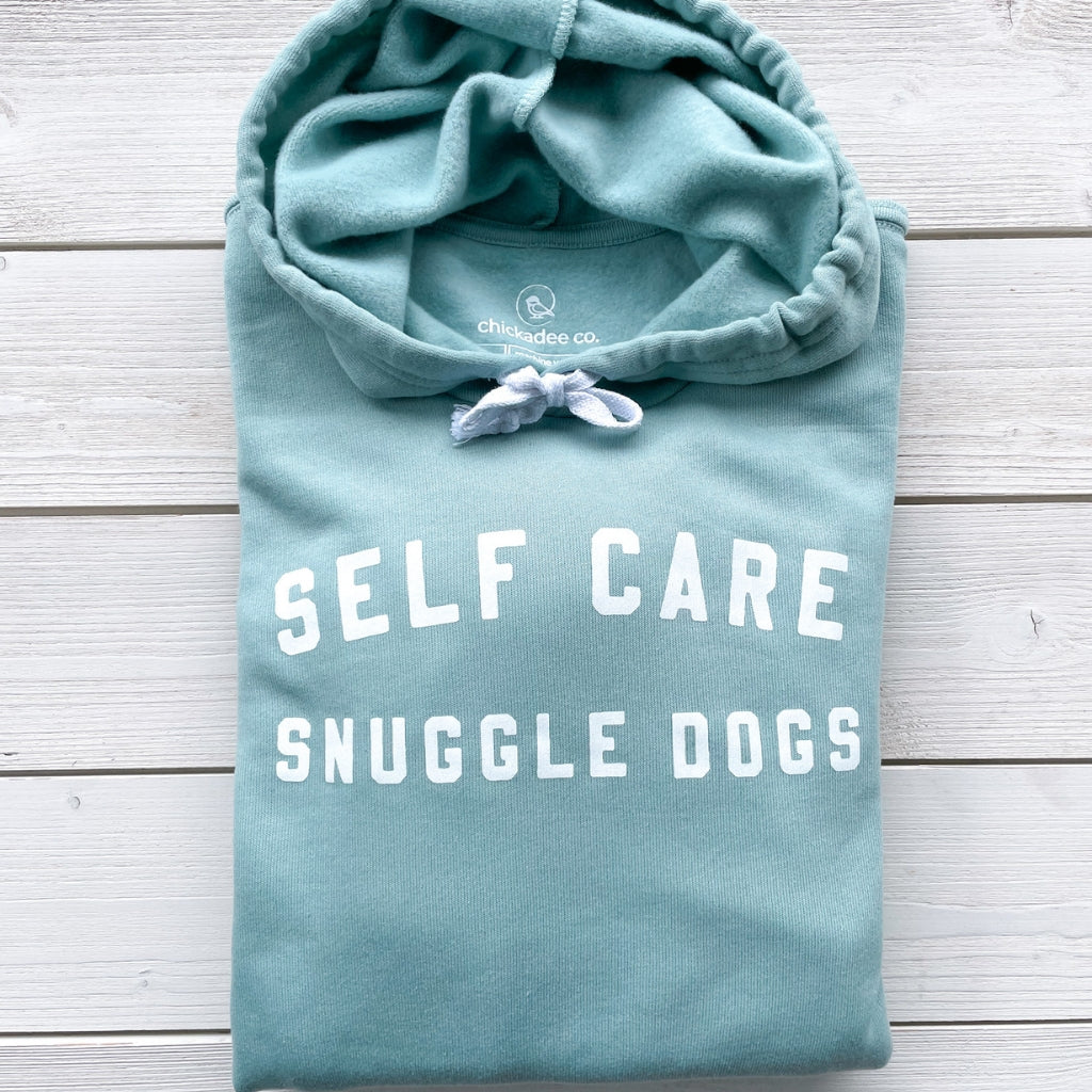 self care snuggle dogs white text saying on light sea green hoodie sweatshirt.  dog apparel.  dog hoodies for humans.  super soft hoodie sweatshirt for dog lovers.