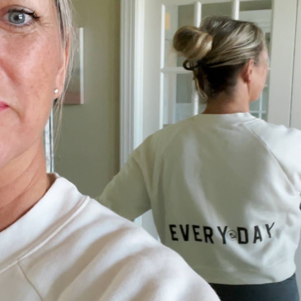 stronger black text saying on vintage white crop sweatshirt. woman wearing active sweatshirt with stronger every day saying. womens crop sweatshirt with leggings & tank top active style.