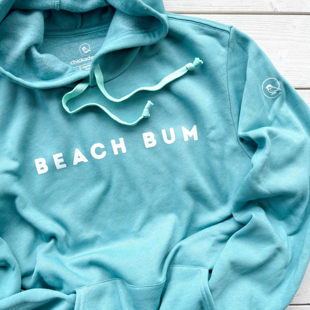 Light blue hoodie with 'BEACH BUM' text on a wooden surface