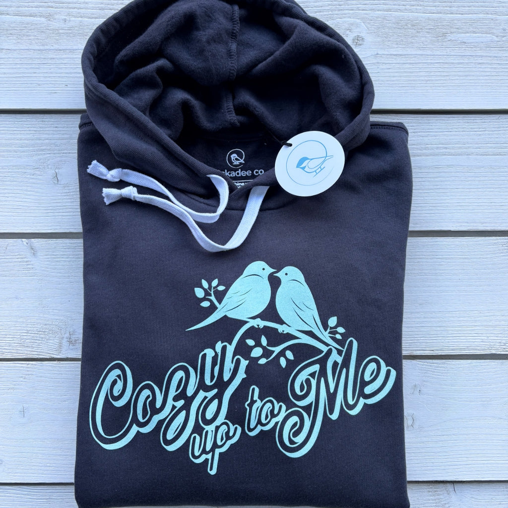 folded charcoal gray hooded sweatshirt with mint green text saying 'cozy up to me' & lovebird graphic.