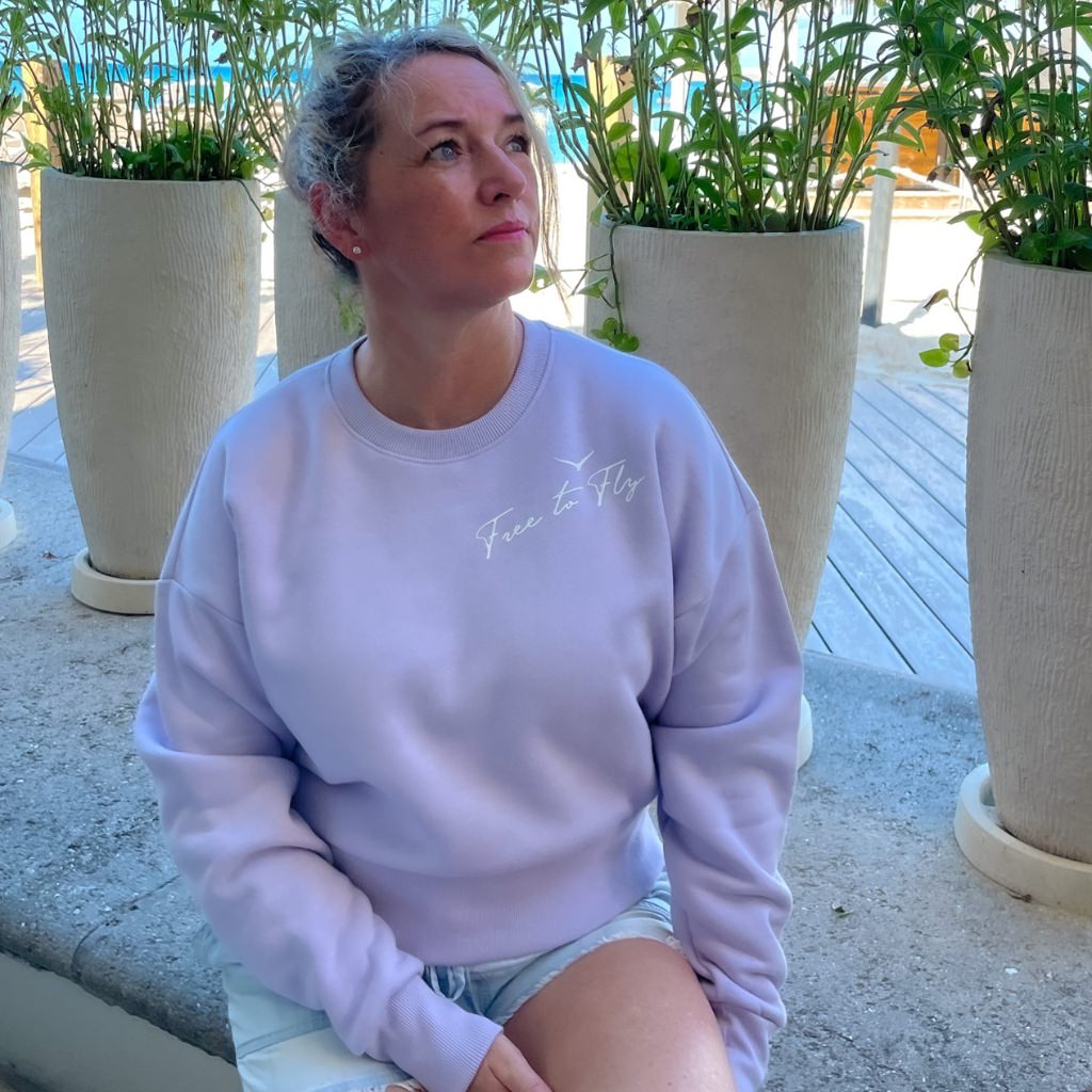 free to fly printed in white ink near the neck line of this womens lavender colored sweatshirt.  wellness apparel.  motivational sweatshirt.