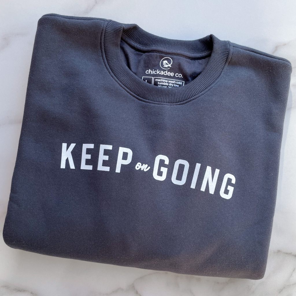 keep on going text in white ink on a dark gray womens sweatshirt.  wellness apparel.  womens active sweatshirt with keep on going intention.