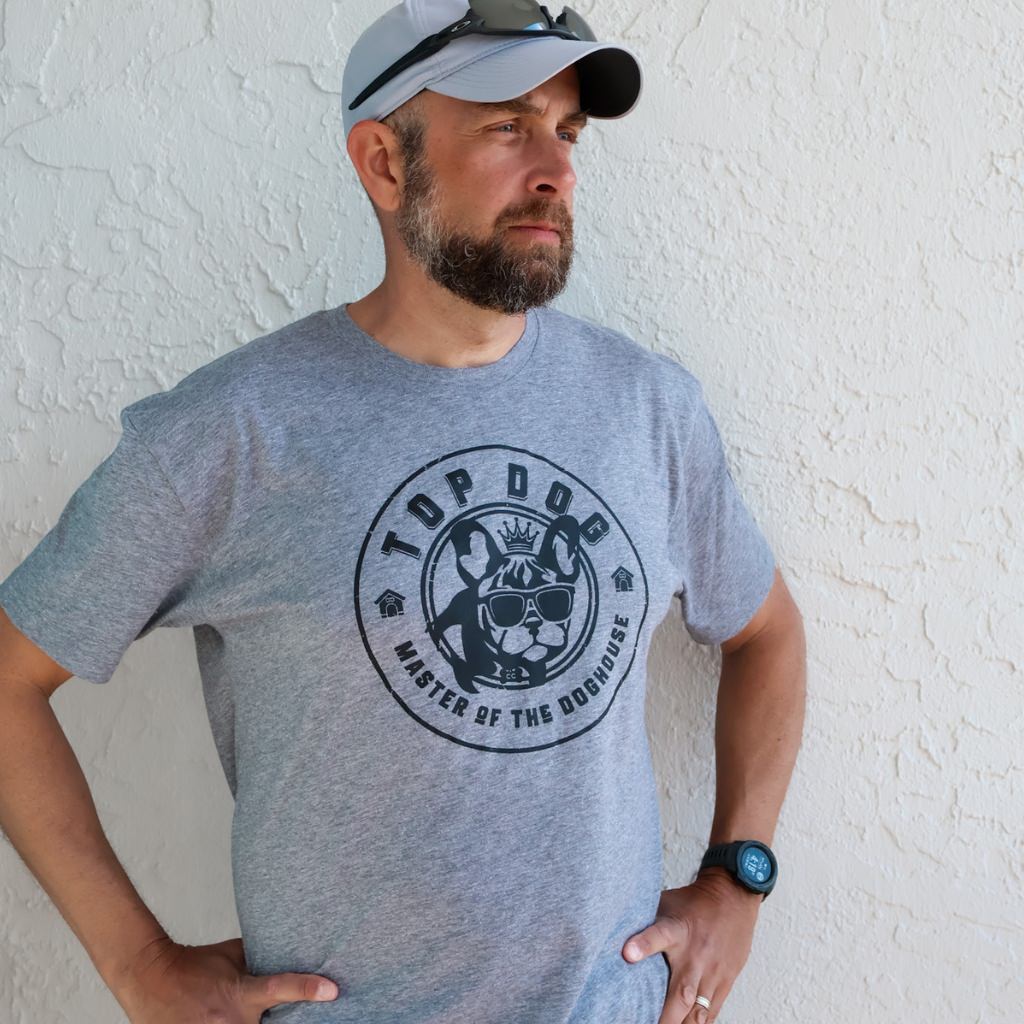 This image features a stylish unisex t-shirt, ideal for dog lovers, known as the "TOP DOG vintage tee." The tee is grey with a classic design that includes a prominent, circular black graphic on the front, depicting a cartoon dog with the text "TOP DOG - Master of the Doghouse.  unisex dog tshirt.  vintage soft tshirt.