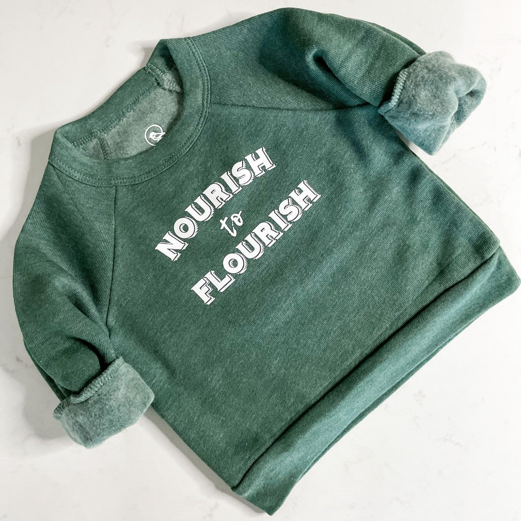 nourish to flourish green unisex toddler crewneck sweatshirt.  super soft wellness apparel.  green sweatshirt with white ink saying ' nourish to flourish'.  kids sweatshirt.