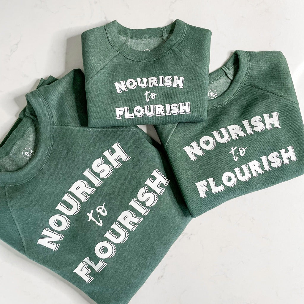 matching family sweatshirts with nourish to flourish saying.  green crew sweatshirts with screen printed nourish to flourish text in white ink.