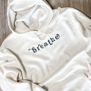 breathe.  breathe hoodie simply laying on a grainy wood table.  chickadee co. wellness hoodie.  inspirational hoodies.
