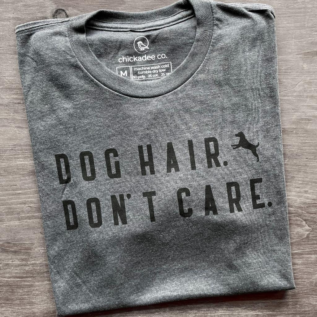 super soft tshirt for men & women.  dog tshirt for humans made by chickadee co.  dark gray tshirt laying flat on a wood table with the words 'dog hair don't care' in black ink.  dog tshirts.