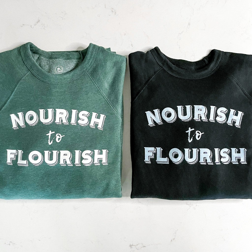 nourish to flourish green & black unisex crewneck sweatshirts.  super soft wellness apparel.  green & black  sweatshirts with white ink saying ' nourish to flourish'.