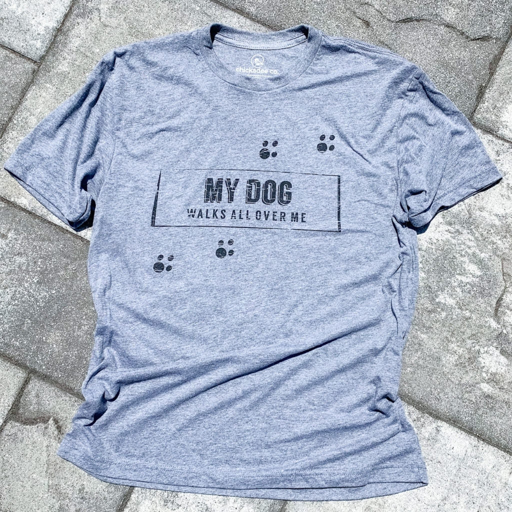 paw prints on front of tshirt. super soft vintage tshirt in grey . unisex grey triblend tshirt for men and women. dog lovers tshirt with my dog walks all over me quote. dog lovers tshirts. my dog walks all over me message. apparel for dog lovers.